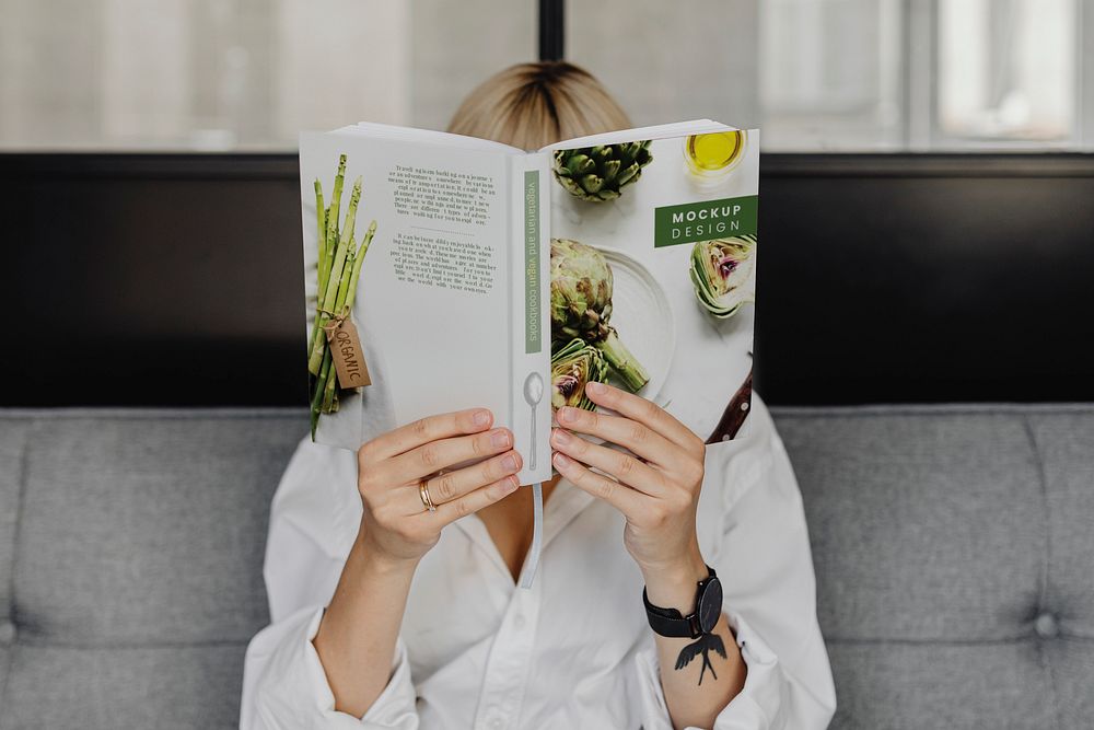 Short blond-haired woman reading a book mockup on a gray couch