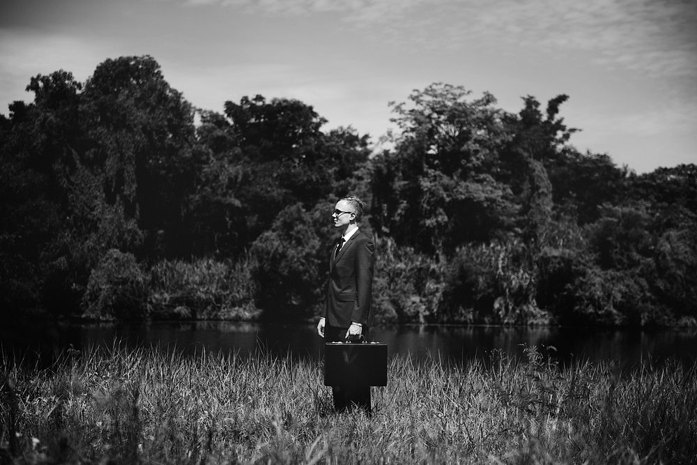 Businessman with his suitcase in nature