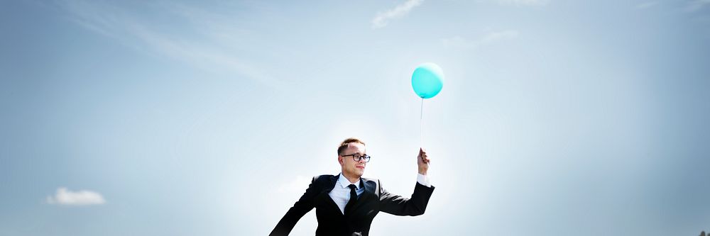 Businessman holding a balloon in nature