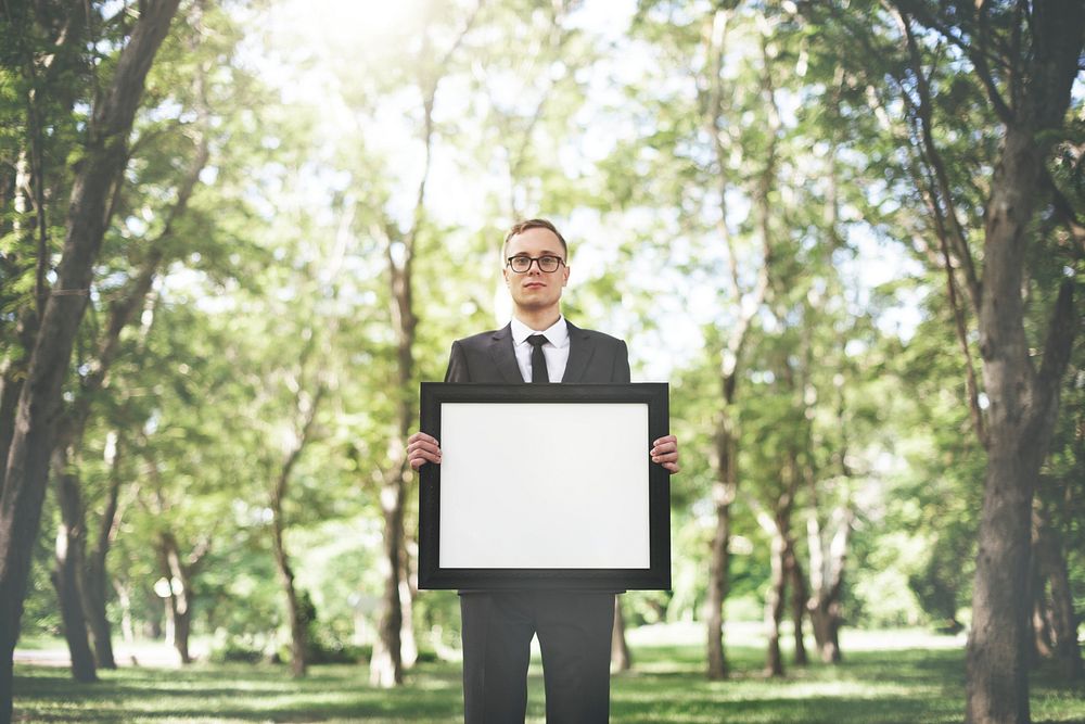 Businessman holding an empty frame in nature