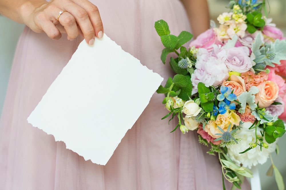 Bride holding a save the date card with a bouquet of flowers