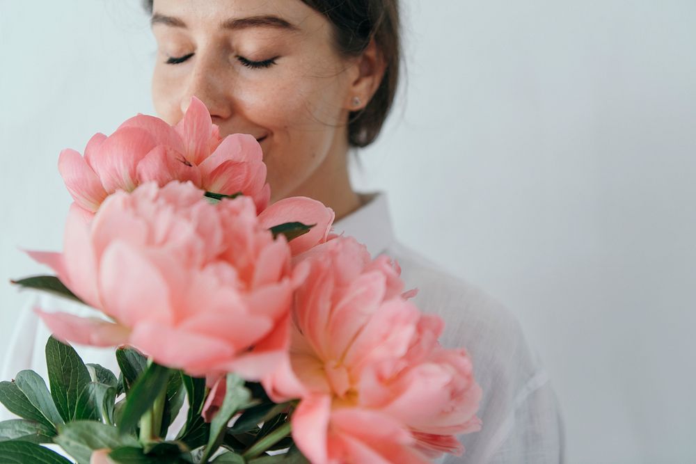 Happy woman smelling a bouquet of coral sunset peony