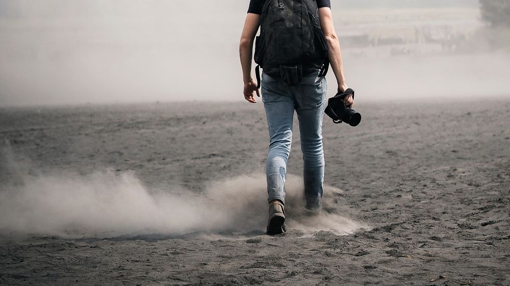 Rear view of a man walking on dusty land