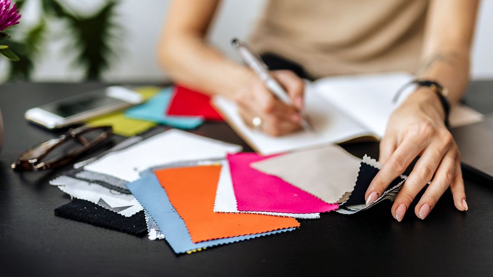 Female fashion designer writing on her notebook