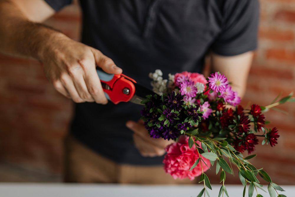Man cutting flowers in his hands while making a bouquet