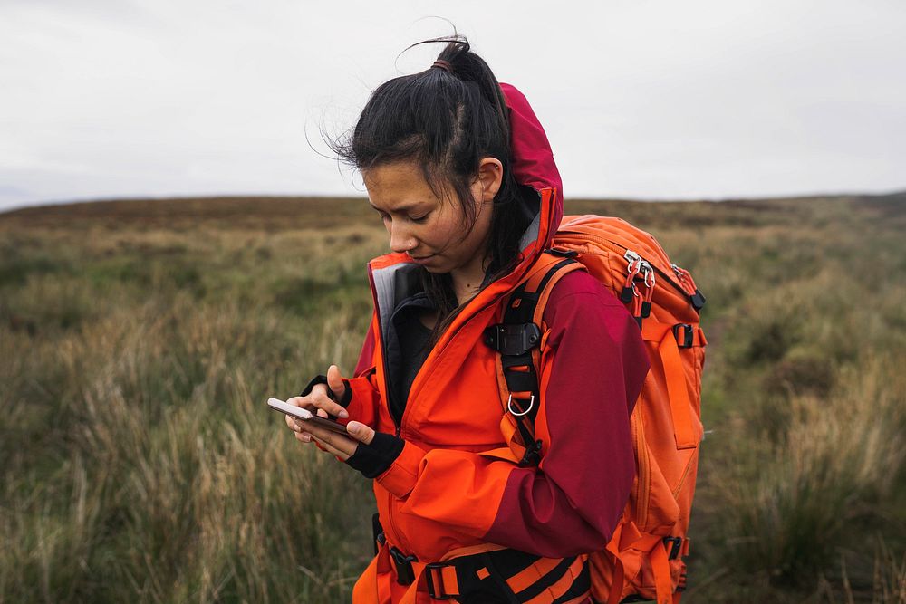Female hiker using her phone in a grass field