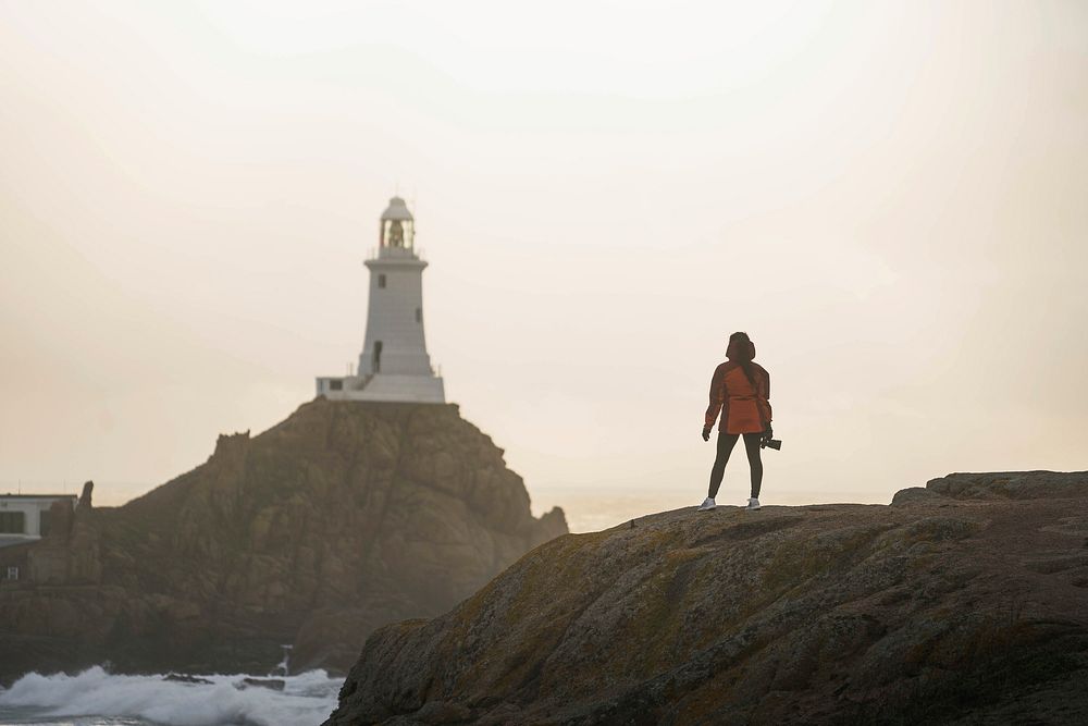 Female traveler at La Corbiere Lighthouse on Isle of Jersey, Scotland