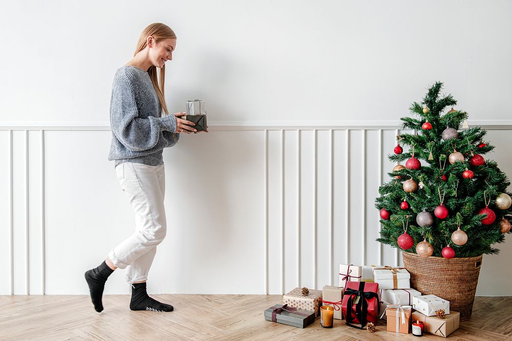 Blond girl decorating a Christmas tree with presents
