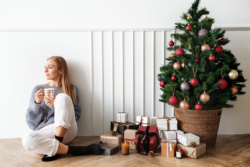 Blond girl sitting next to a Christmas tree