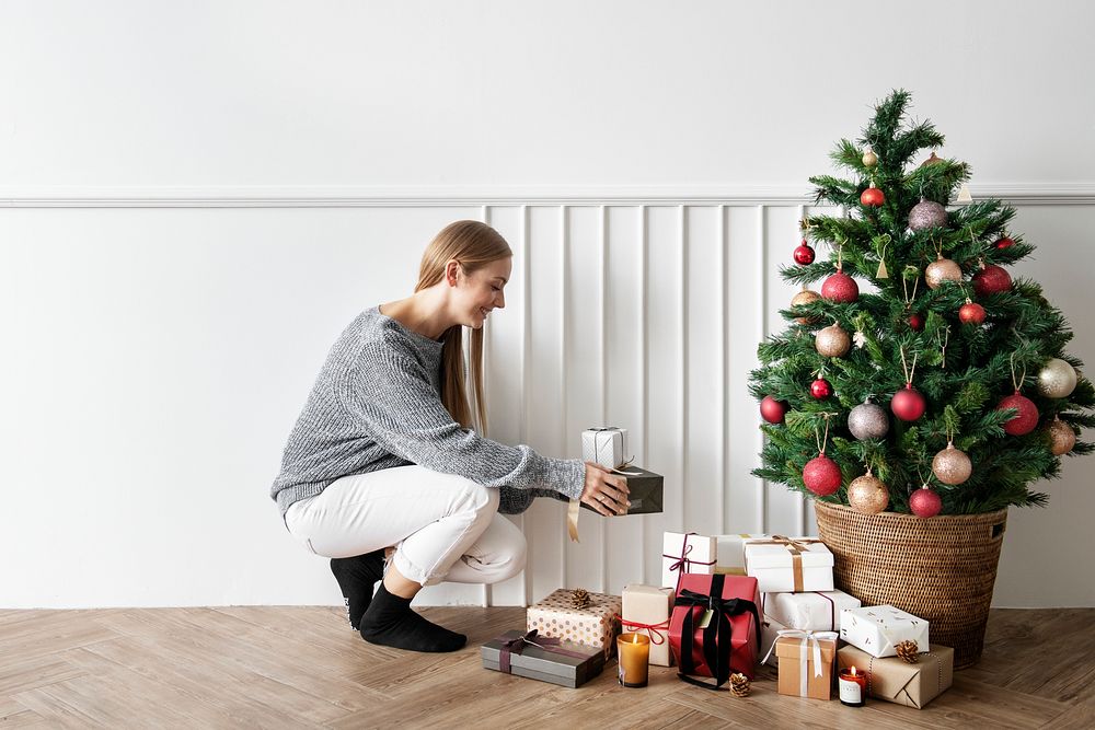 Blond girl decorating a Christmas tree with presents