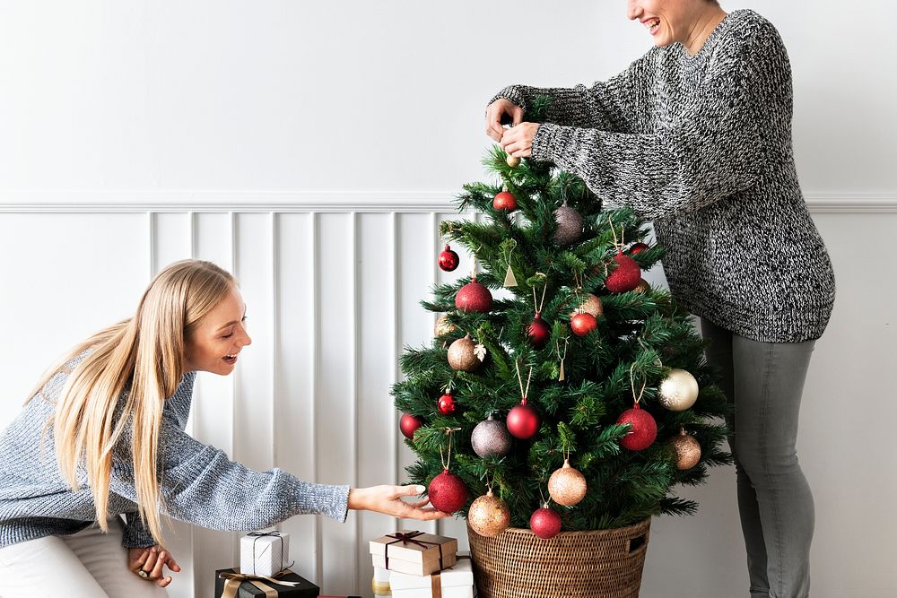 Woman decorating a Christmas tree with ornaments