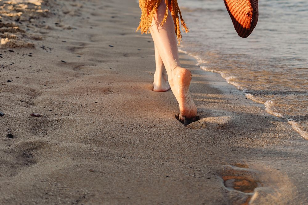 Girl in a brown dress walking alone the beach