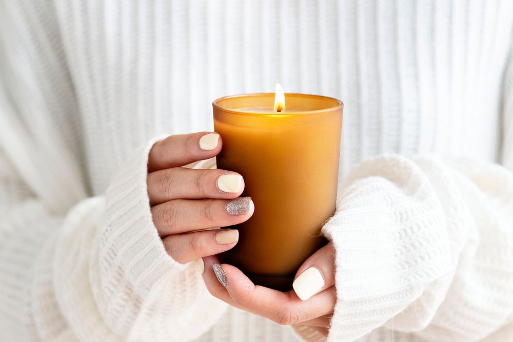 Woman in a white sweater holding a candle on her hand