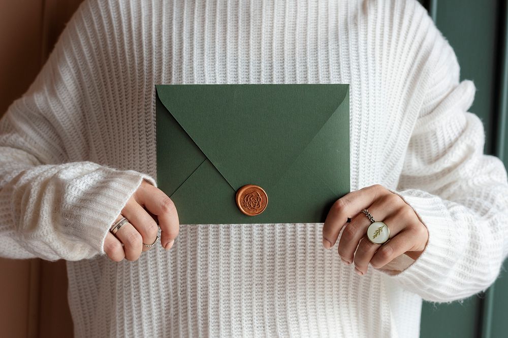 Woman in a white sweater holding a green envelope