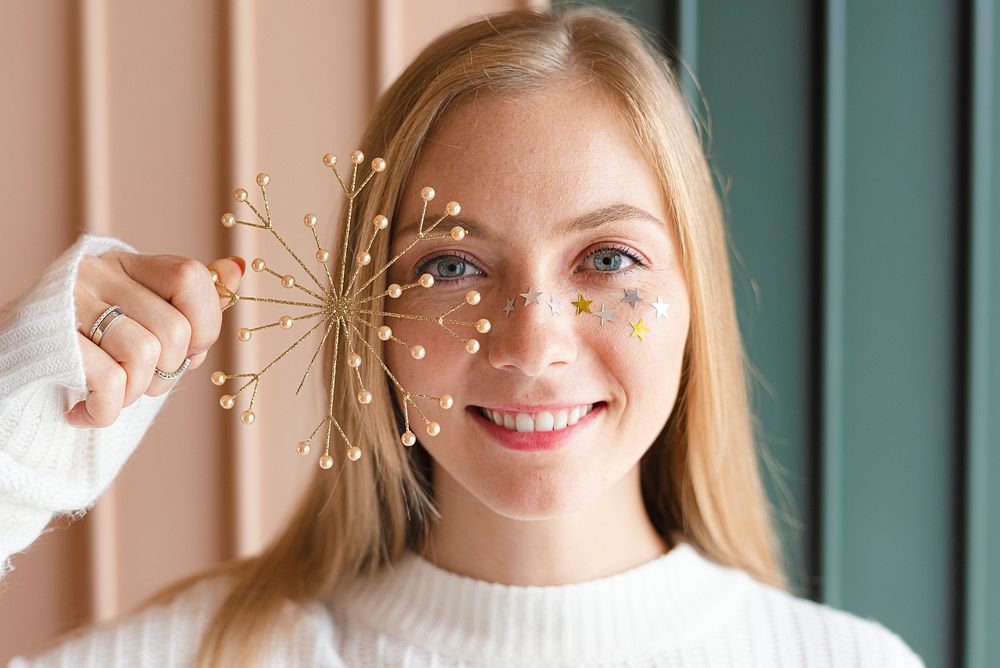 Cheerful woman holding a glittery gold snowflake