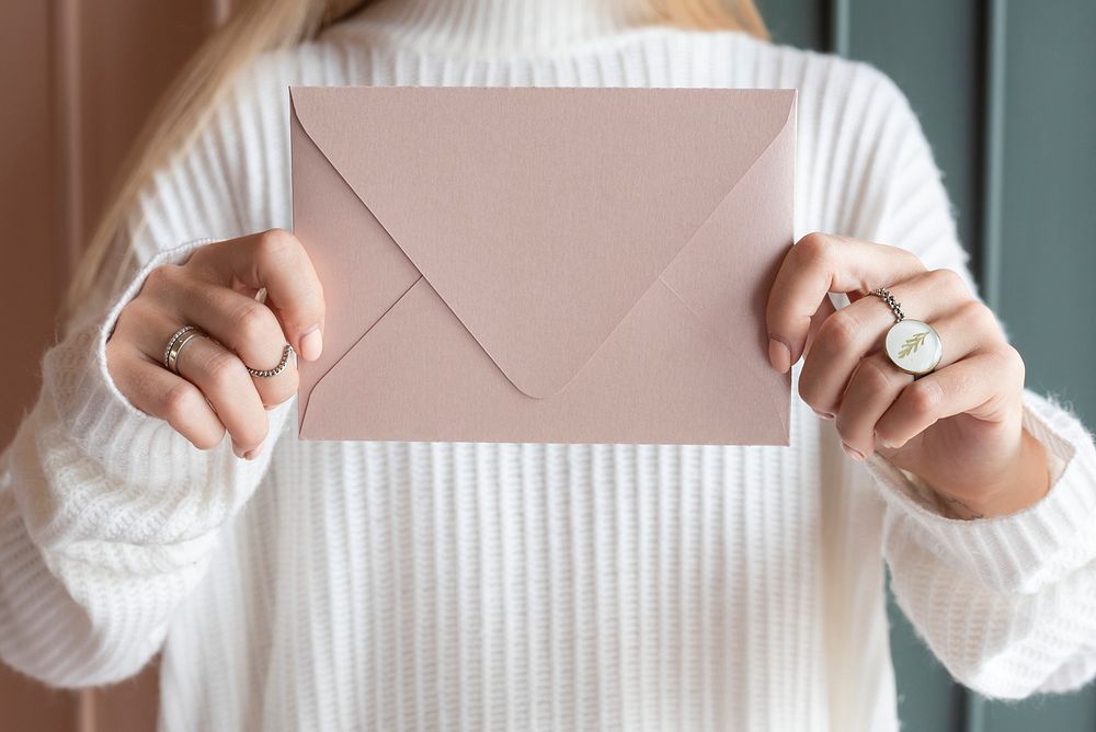 Woman in a white sweater holding a pink envelope