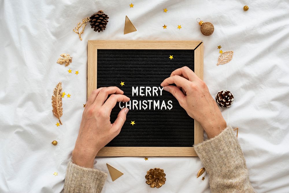 Woman making a Merry Christmas word on a black text board