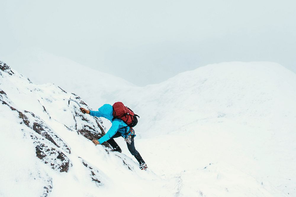 Mountaineer using an ice axe  to climb Forcan Ridge in Glen Shiel, Scotland