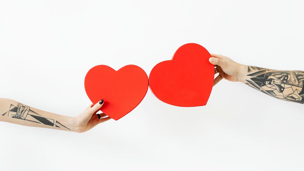 Tattooed hands holding red hearts wallpaper
