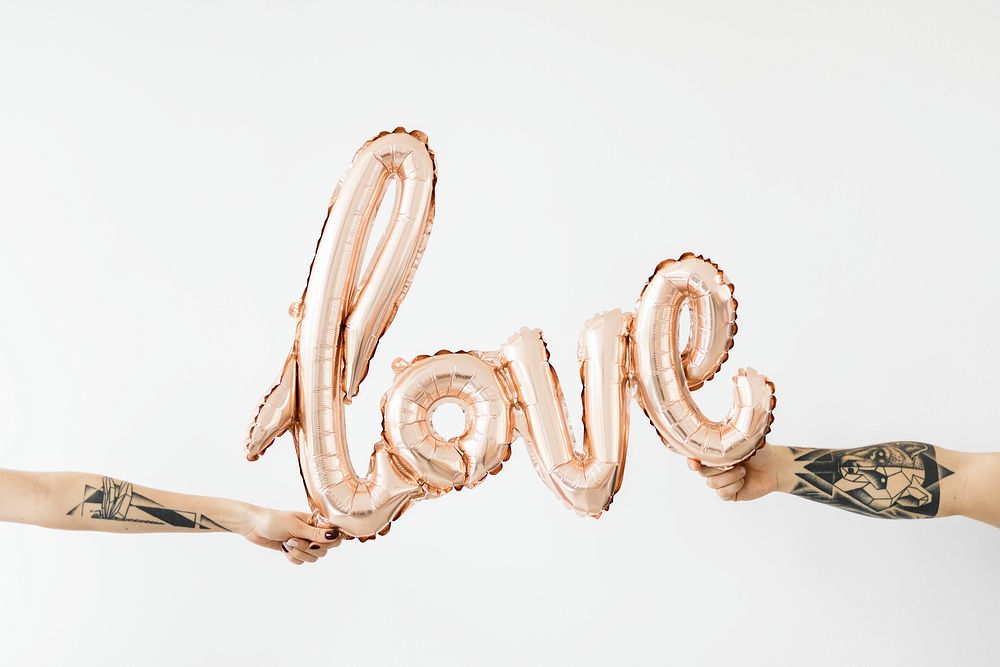 Hands holding a glossy rose gold love balloon