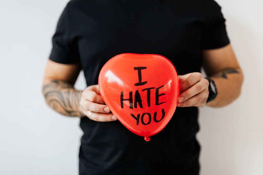 Man showing a heart red balloon with I hate you on it