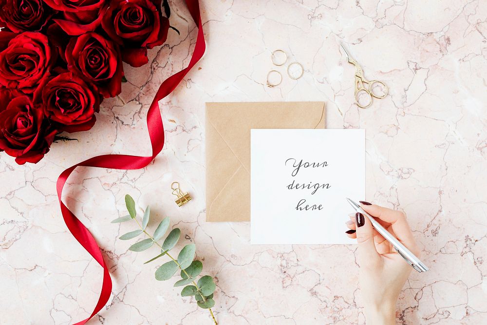 Woman writing on a card mockup by a bouquet of red roses 