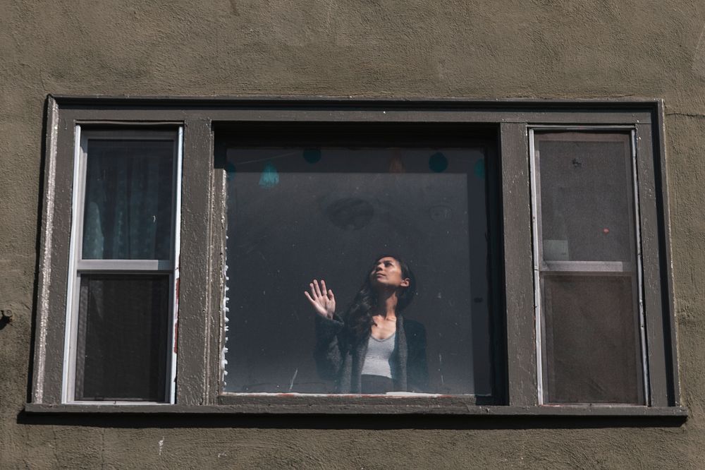 Woman staring out the window during the coronavirus lockdown. 