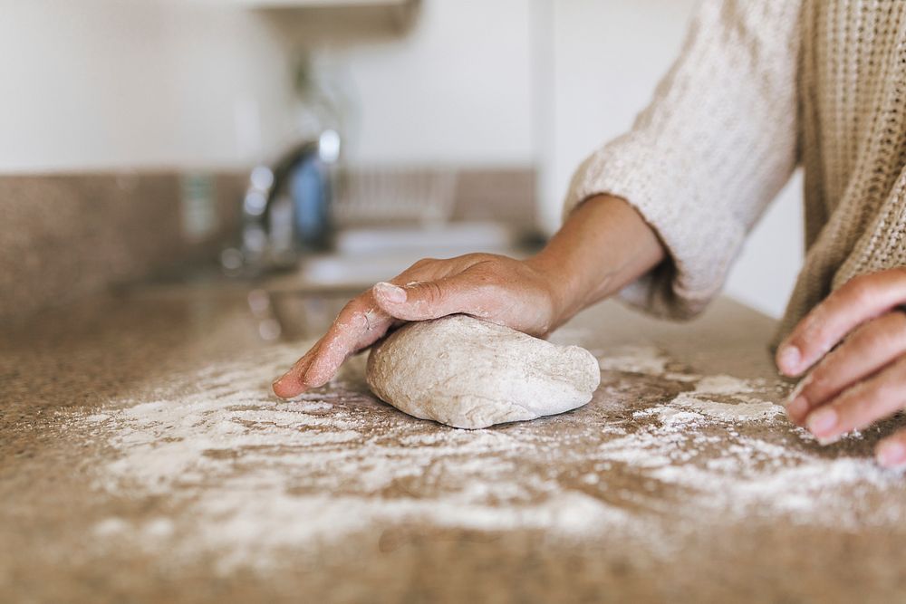 Woman kneading a sourdough in her kitchen during coronavirus quarantine