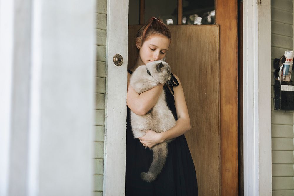 Girl with her pet cat standing by the door during the coronavirus lockdown