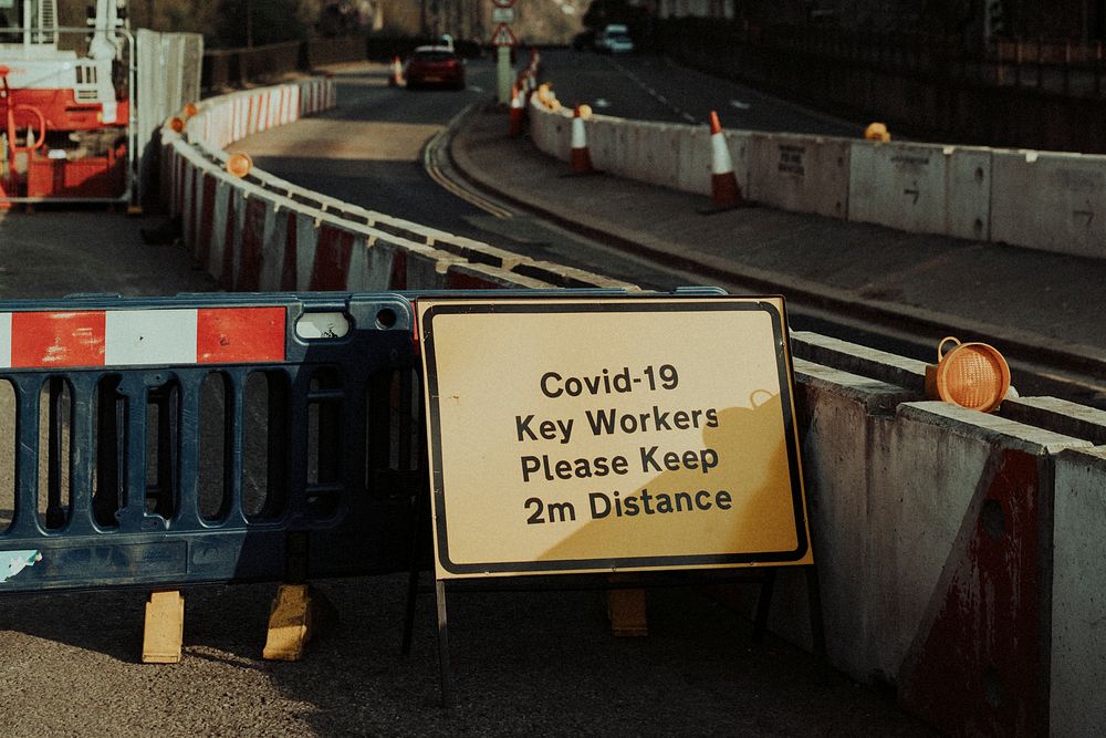 Physical distancing warning sign for roadside construction workers during the covid-19 pandemic