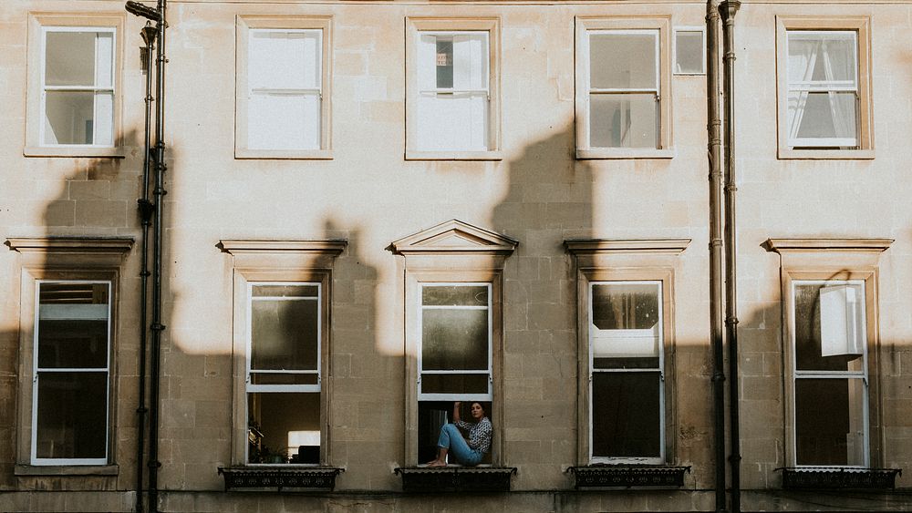 Woman in the window of her apartment during self quarantine due to the covid-19 pandemic in Britain. APRIL 4, 2020 - BATH, UK