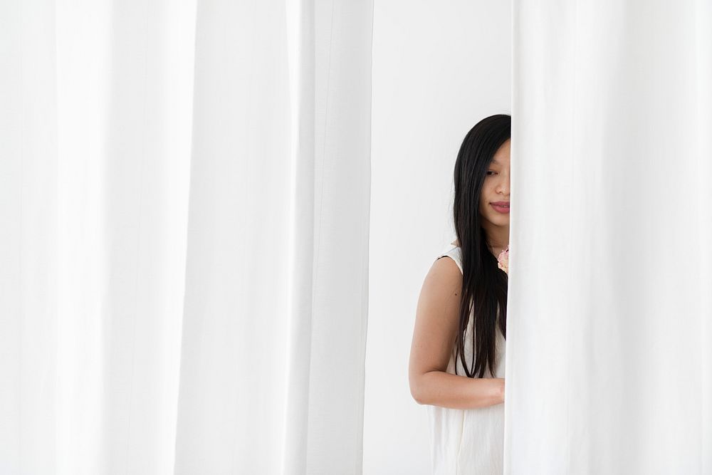 Asian woman with a flower behind a white curtain
