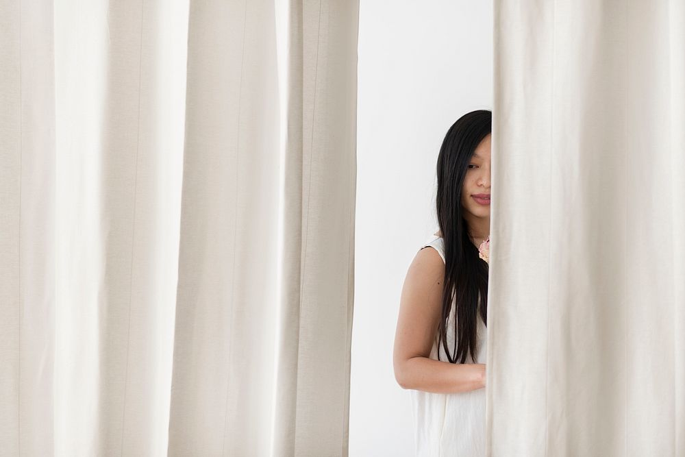 Asian woman with a flower behind a white curtain