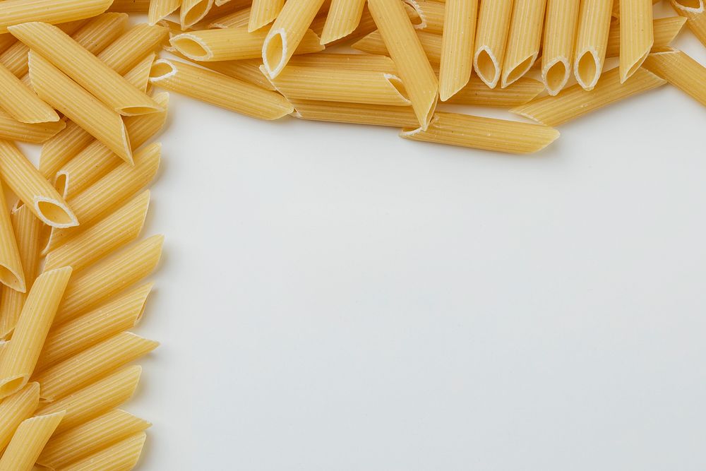 Uncooked penne pasta frame on white