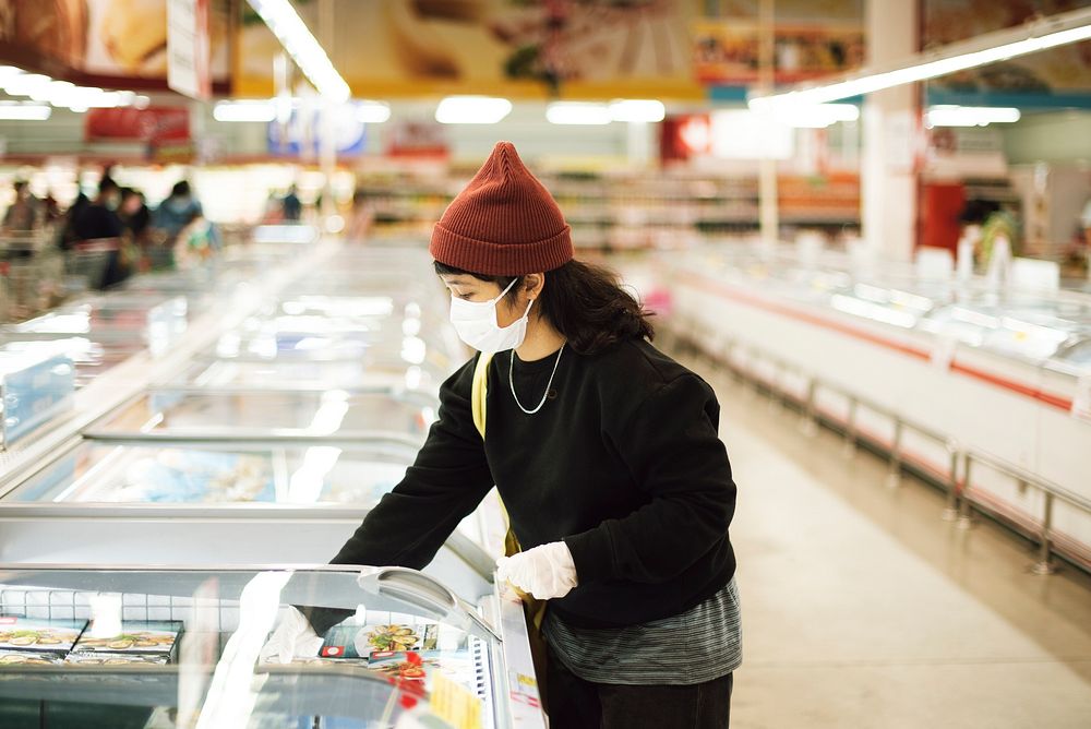 Woman with a medical mask buying frozen food during coronavirus pandemic