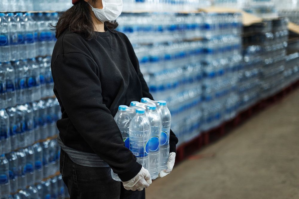 Woman carrying drinking waters with gloved hands during coronavirus pandemic