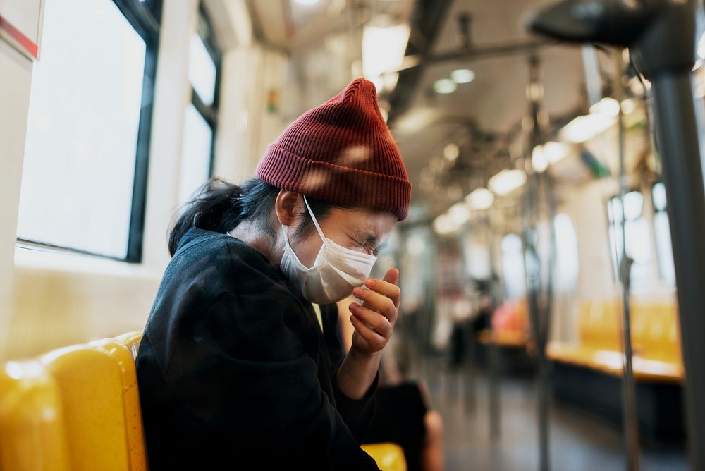 Sick woman in a mask sneezing in a train during coronavirus pandemic