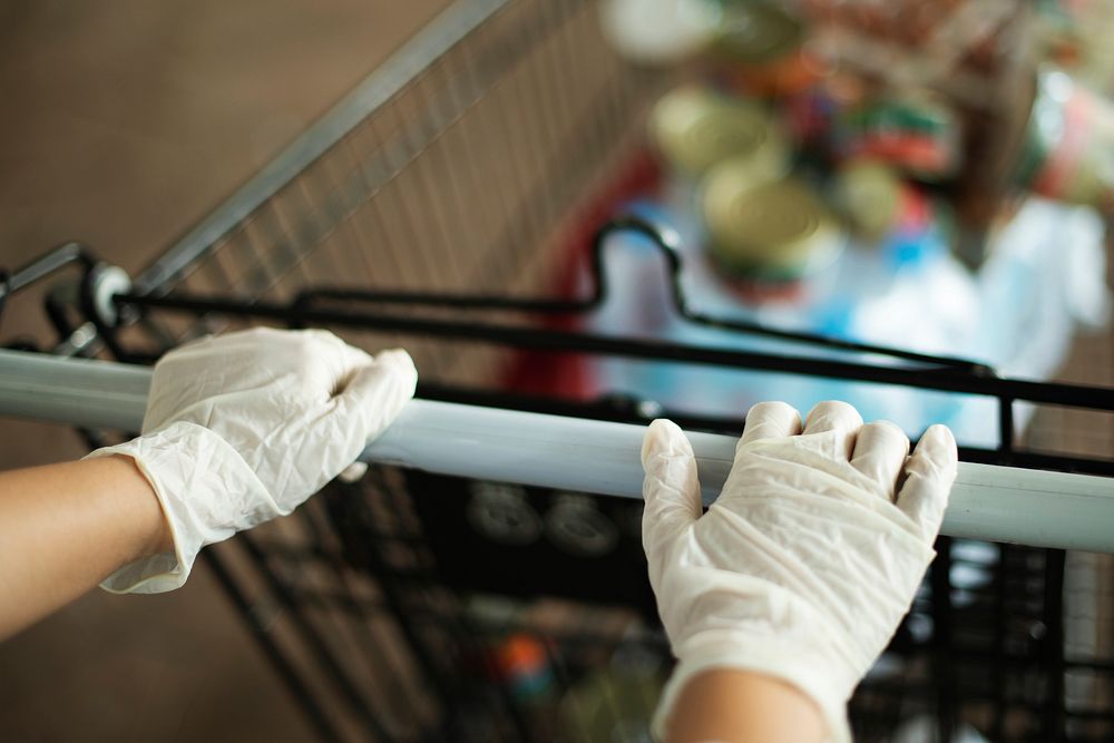 Woman wearing gloves to prevent coronavirus while using a shopping cart 