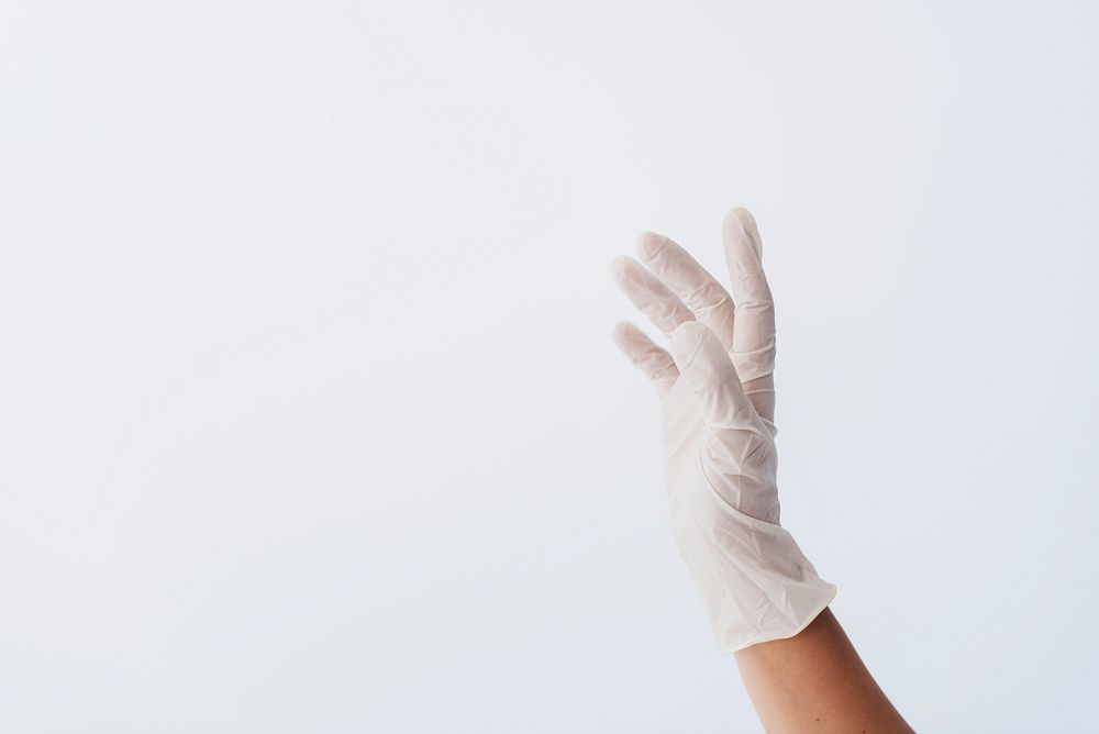 Hand wearing a white latex glove to prevent coronavirus contamination