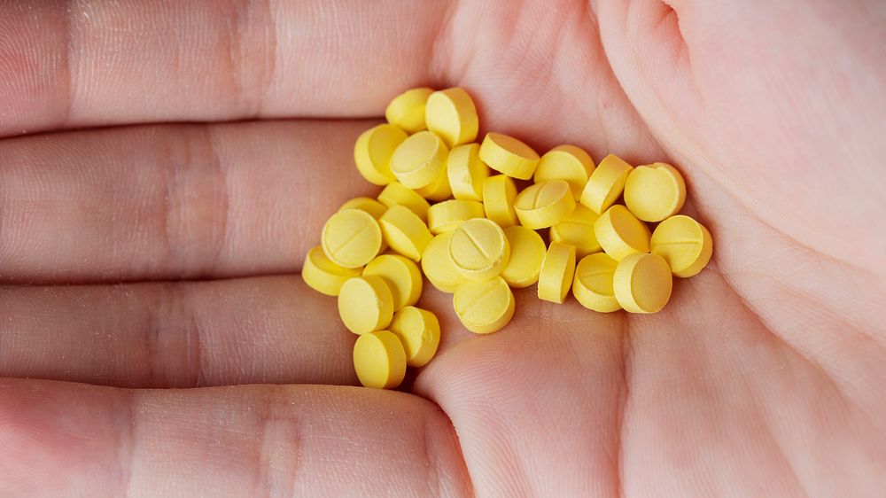 Woman with a handful of yellow pills