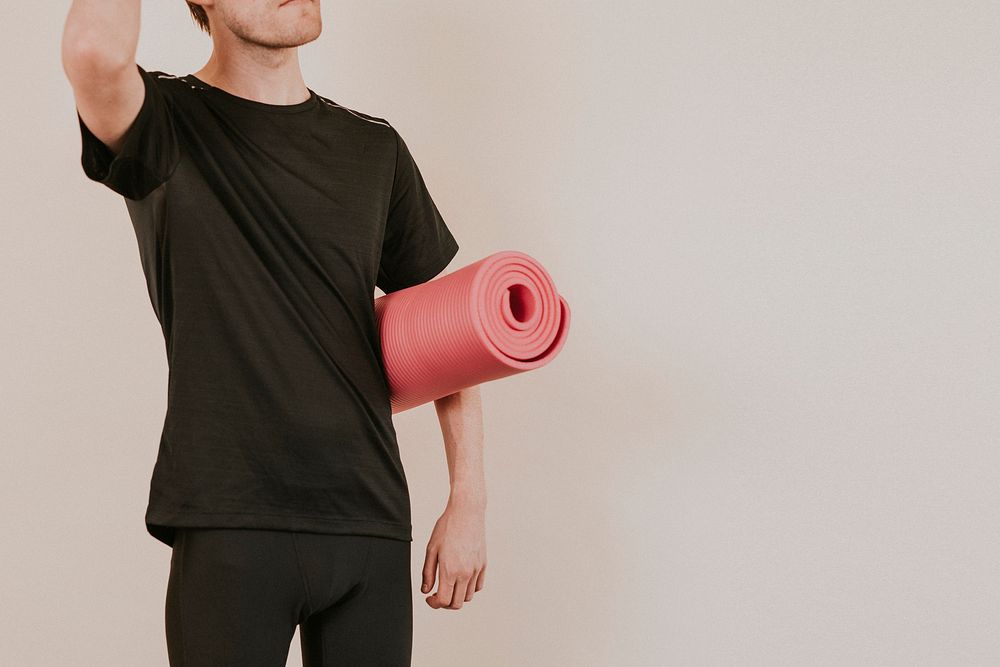 Man in black sport shirt with pink yoga mat studio shot
