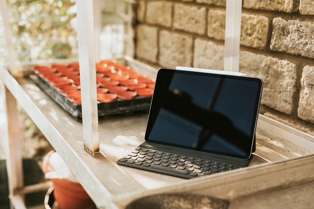 Black tablet with keyboard on a gardening wooden table