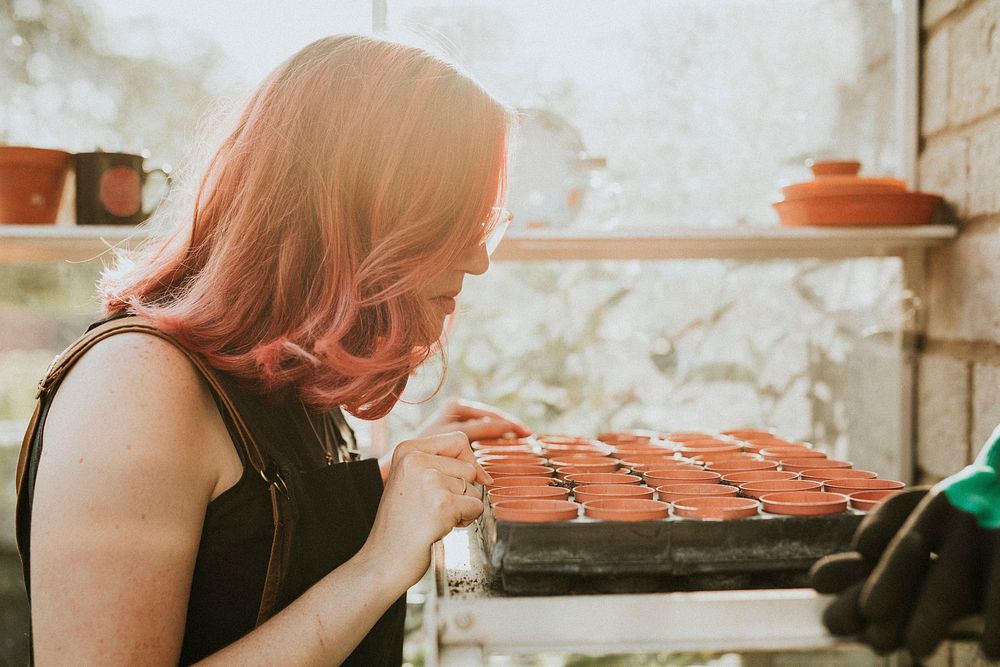 Woman with planting pot rows in greenhouse