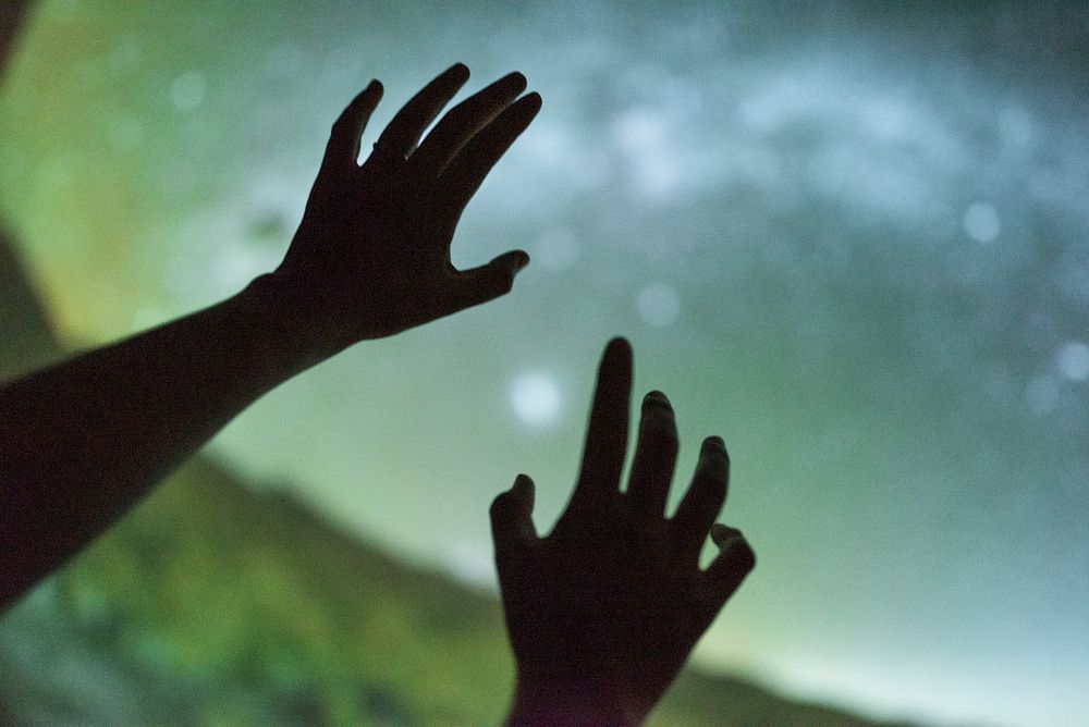 Girl reaching towards the planets at the planetarium 