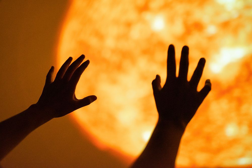 Girl reaching towards the sun at the planetarium
