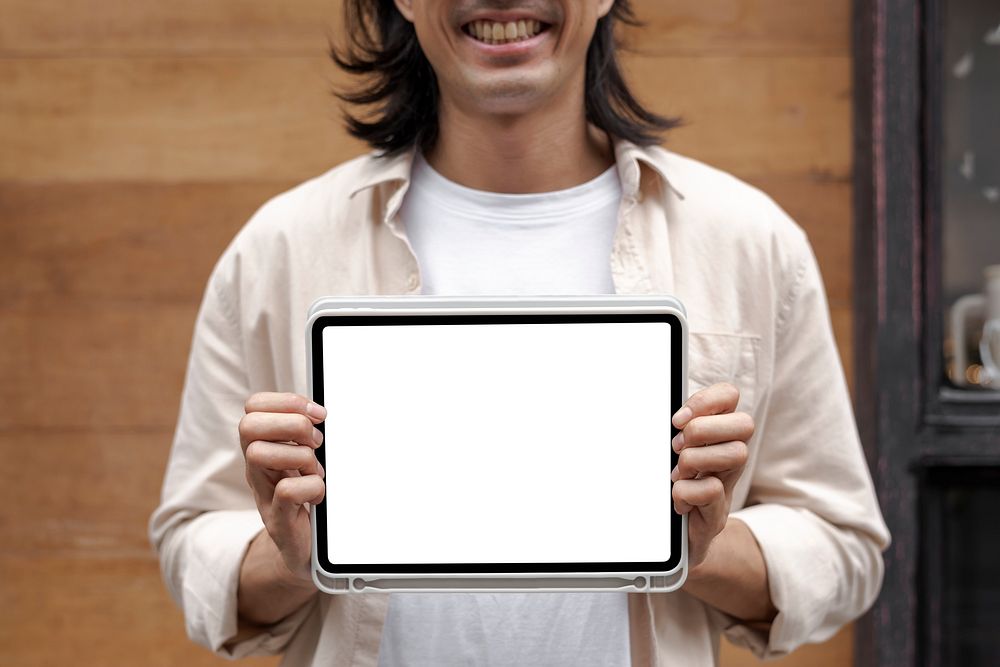 Digital tablet screen mockup psd in the hands of a casual Japanese designer