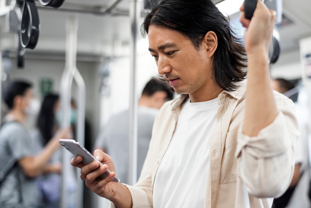 Japanese man scrolling on his phone while on the train