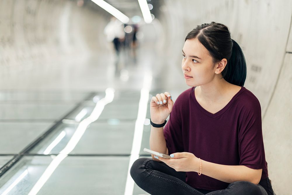 Girl sitting on the floor in a tunnel and texting to a friend