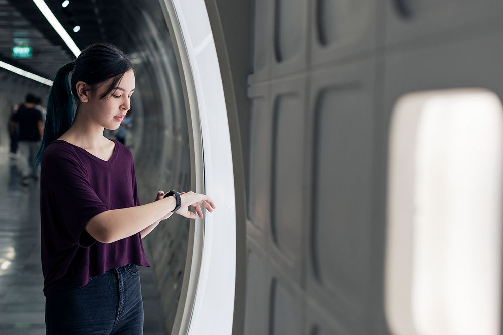 Girl connecting smartwatch to a screen in an underground tunnel