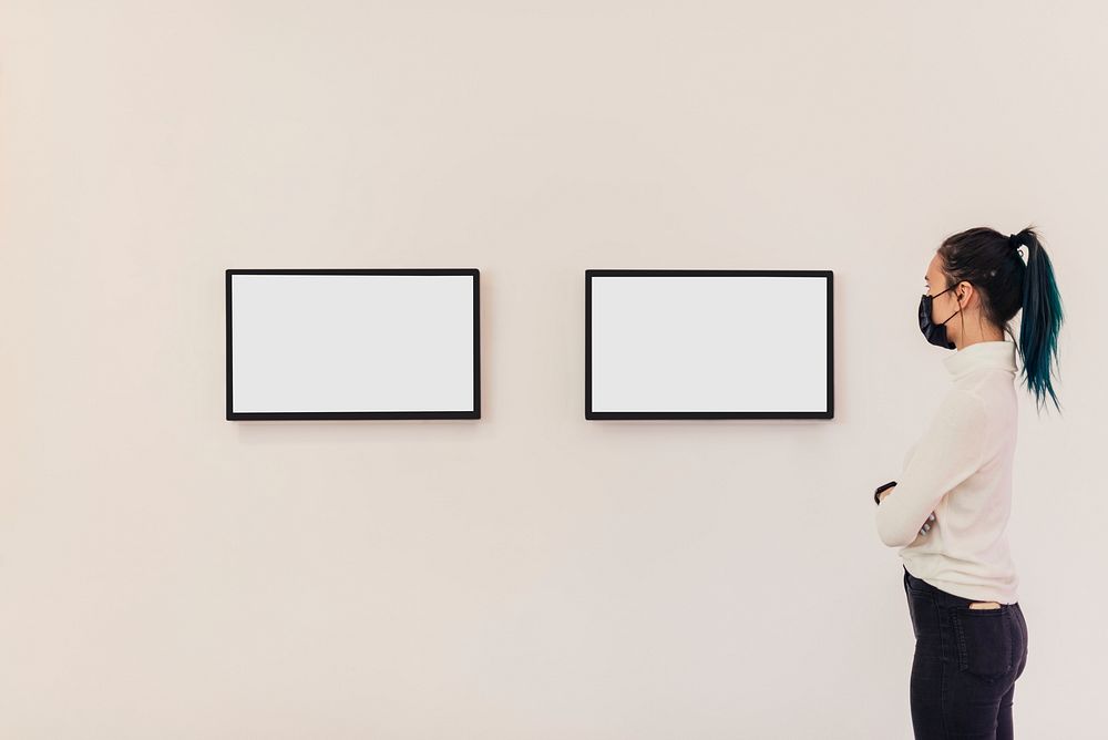 Girl looking at digital frames on a white gallery wall